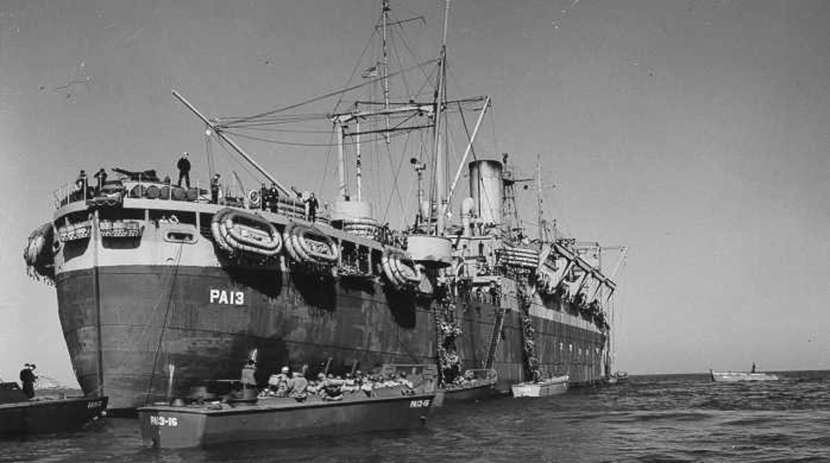 USS Joseph T. Dickman (APA-13) at anchor while disembarking troops, date and location unknown.