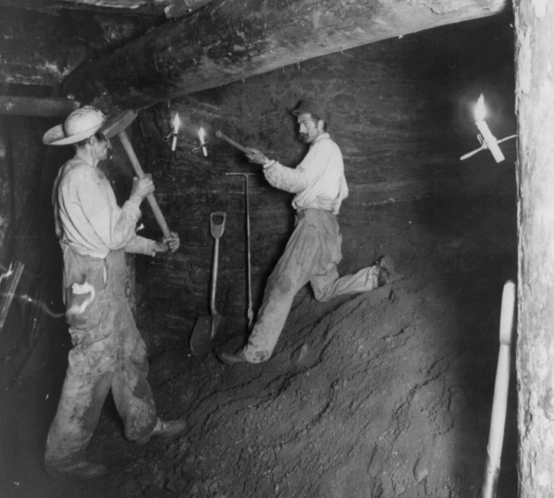 Two coal miners working in a coal mine by candlelight, 1909.