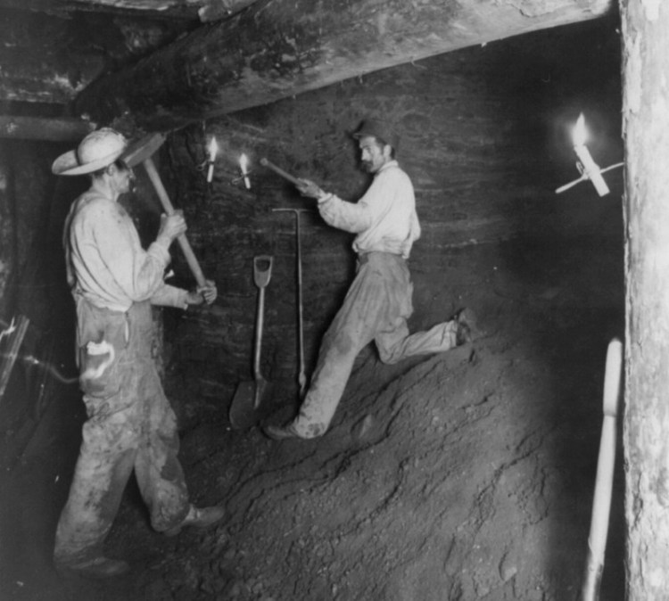 Two coal miners working in a coal mine by candlelight, 1909.