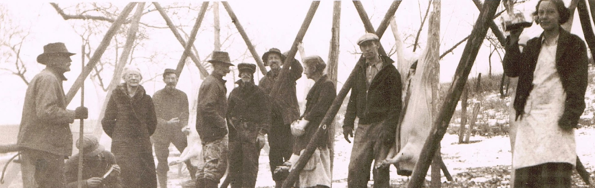 Men and women gathered around a butchered pic, circa 1930.